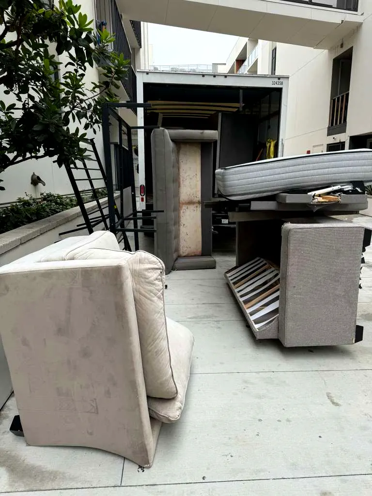 Mattresses, a couch and a bed frame carried out and staged at the loading area during a Baka Junk Removal apartment move-out