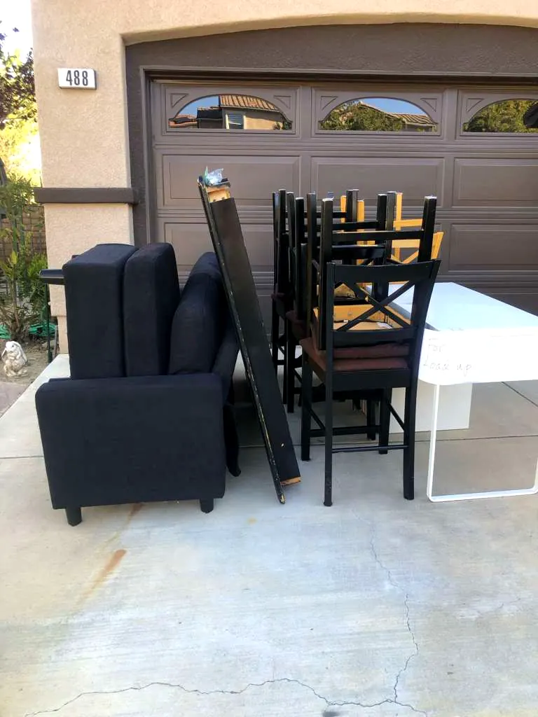 Sofa, dining chairs and a desk staged in a Los Angeles driveway for a Baka Junk Removal curbside furniture pickup